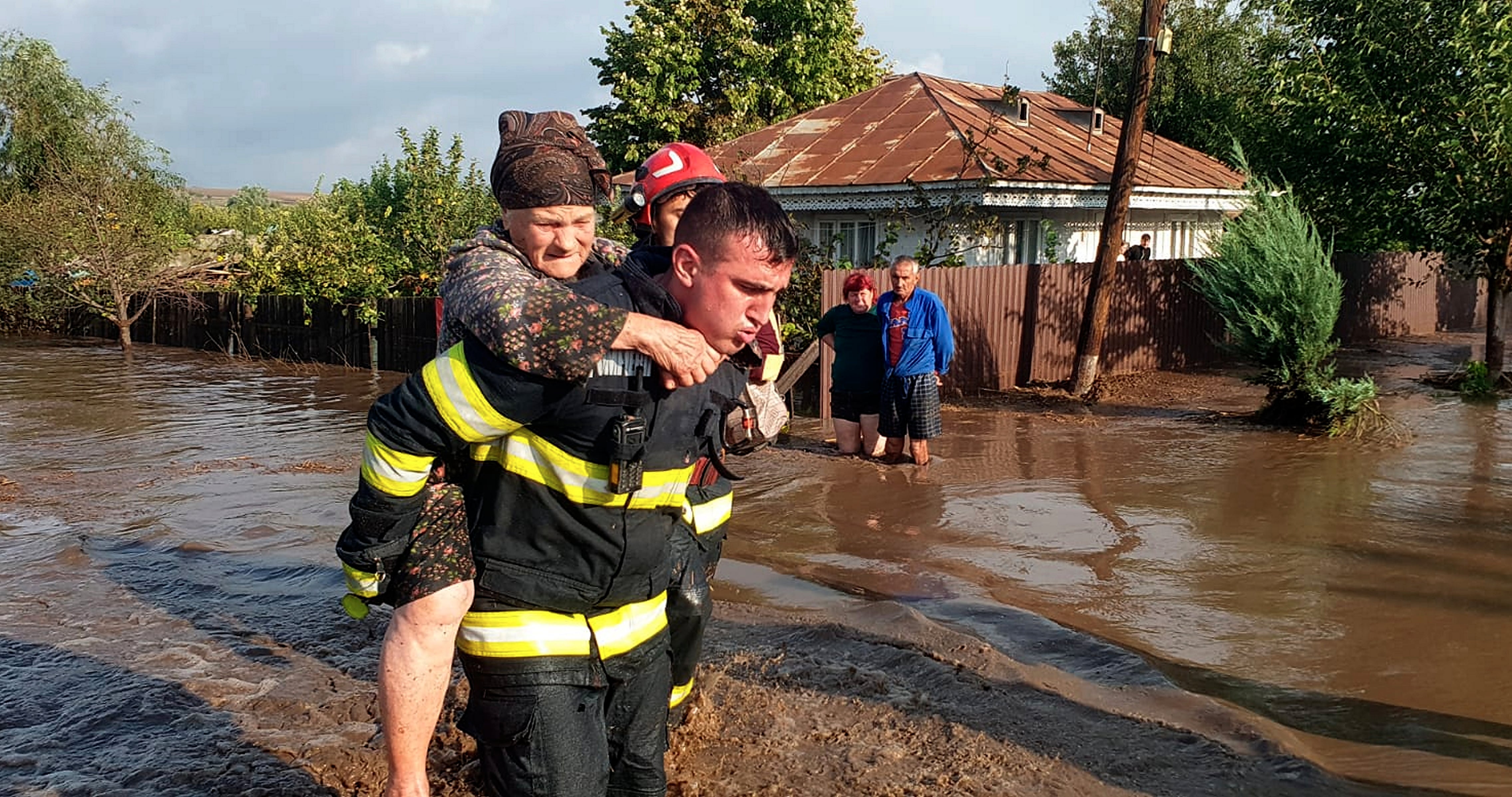 Un trabajador de los servicios de emergencias rescata a una mujer afectada por las inundaciones en Rumanía