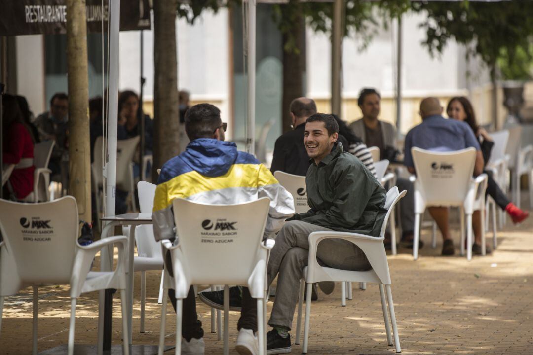 Personas consumiendo en los veladores de un bar (imagen de archivo)