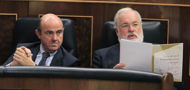 El ministro de Economía, Luis de Guindos (i), junto al ministro de Agricultura, Miguel Arias Cañete, en la sesión de control al Gobierno en el Congreso de los Diputados