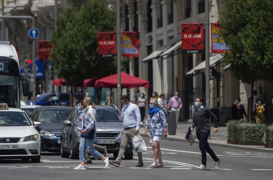 Varias personas con mascarillas cruzan un paso para peatones en Madrid