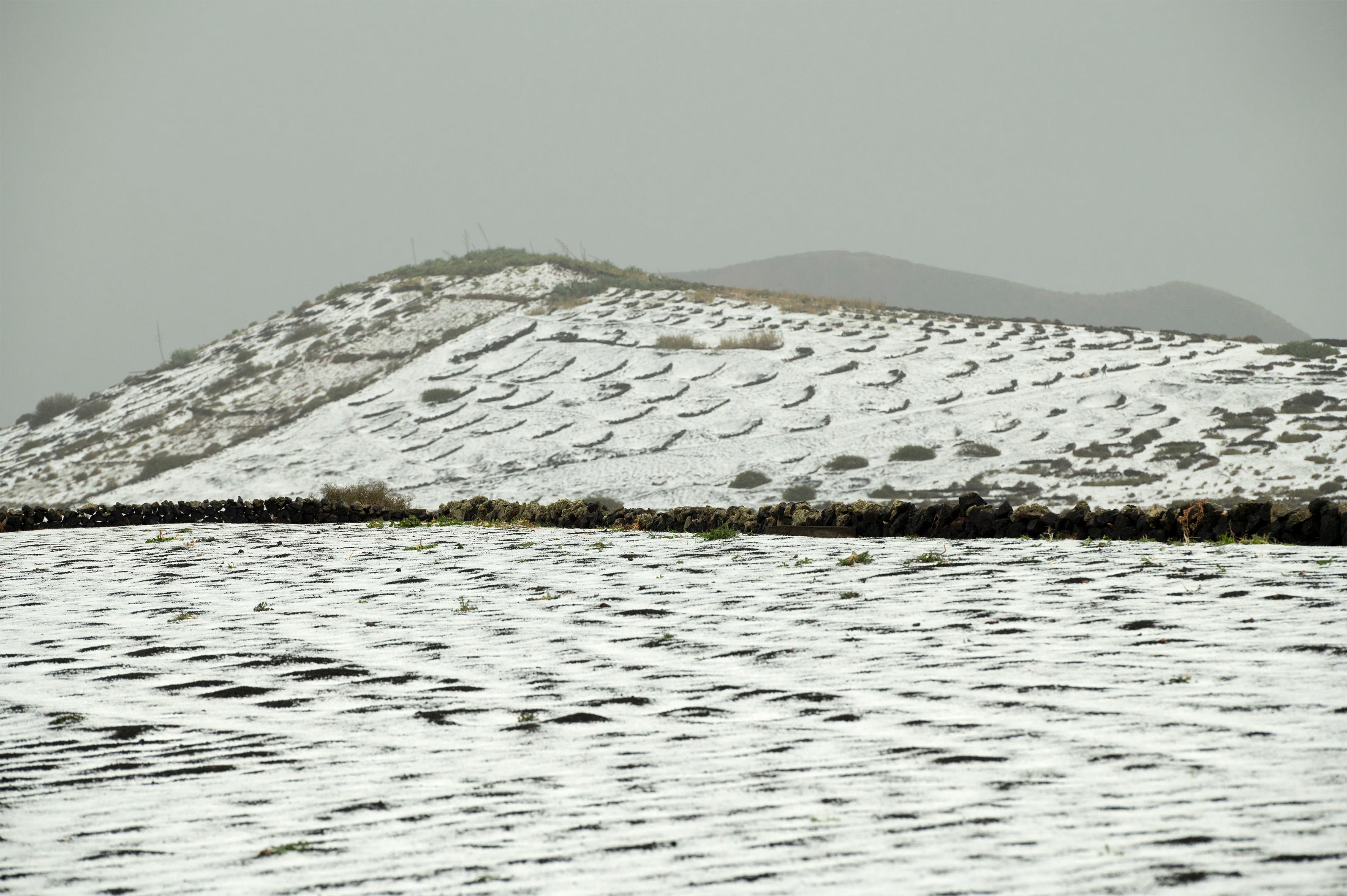 GRAFCAN5281. TÍAS (LANZAROTE), 04/02/2023.- Lanzarote ha sido protagonista este sábado de un temporal de lluvia y granizo que ha afectado a toda la isla y que ofrece imágenes poco habituales en las islas Canarias. En la imagen, una loma cubierta de granizo en el pueblo de Masdache, en el municipio de Tías. EFE/ Adriel Perdomo
