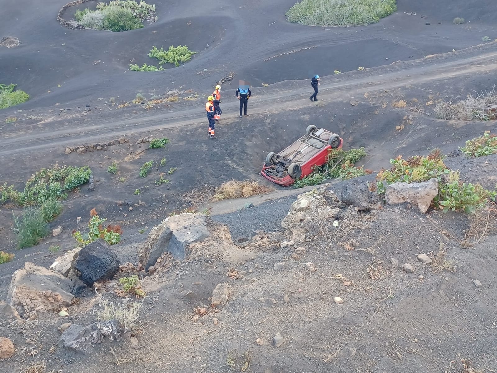 Bomberos y agentes de la Policía Local de Yaiza junto al vehículo volcado.