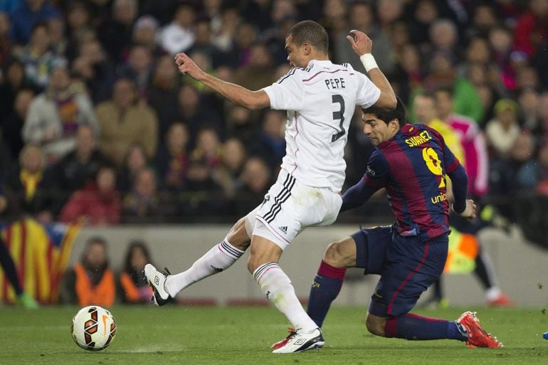 El delantero del F. C. Barcelona, Luis Suárez (d), golpea el balón ante el defensa del Real Madrid, Pepe, consiguiendo el segundo gol del equipo blaugrana