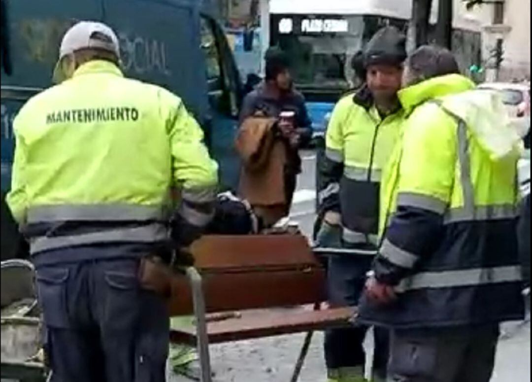 Momento en el que los operarios del Ayuntamiento de Madrid retiran el banco frente al Samur Social