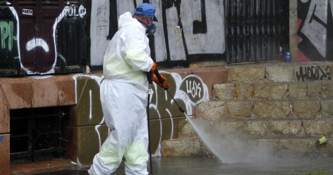 Un trabajador de limpieza desinfecta unas escaleras.