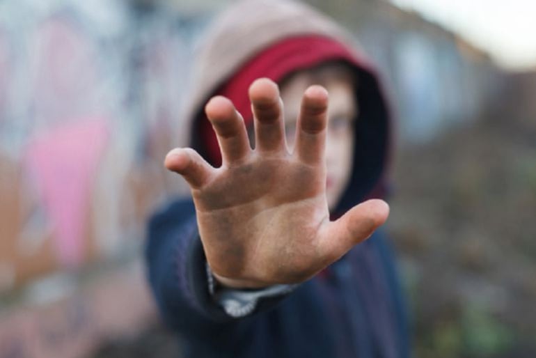 Un niño extiende la mano hacia la cámara. 