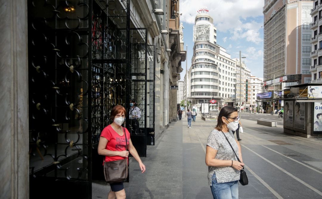 Varias personas salen de una tienda de moda en la Gran Vía abierta durante la fase 1 de la desescalada.