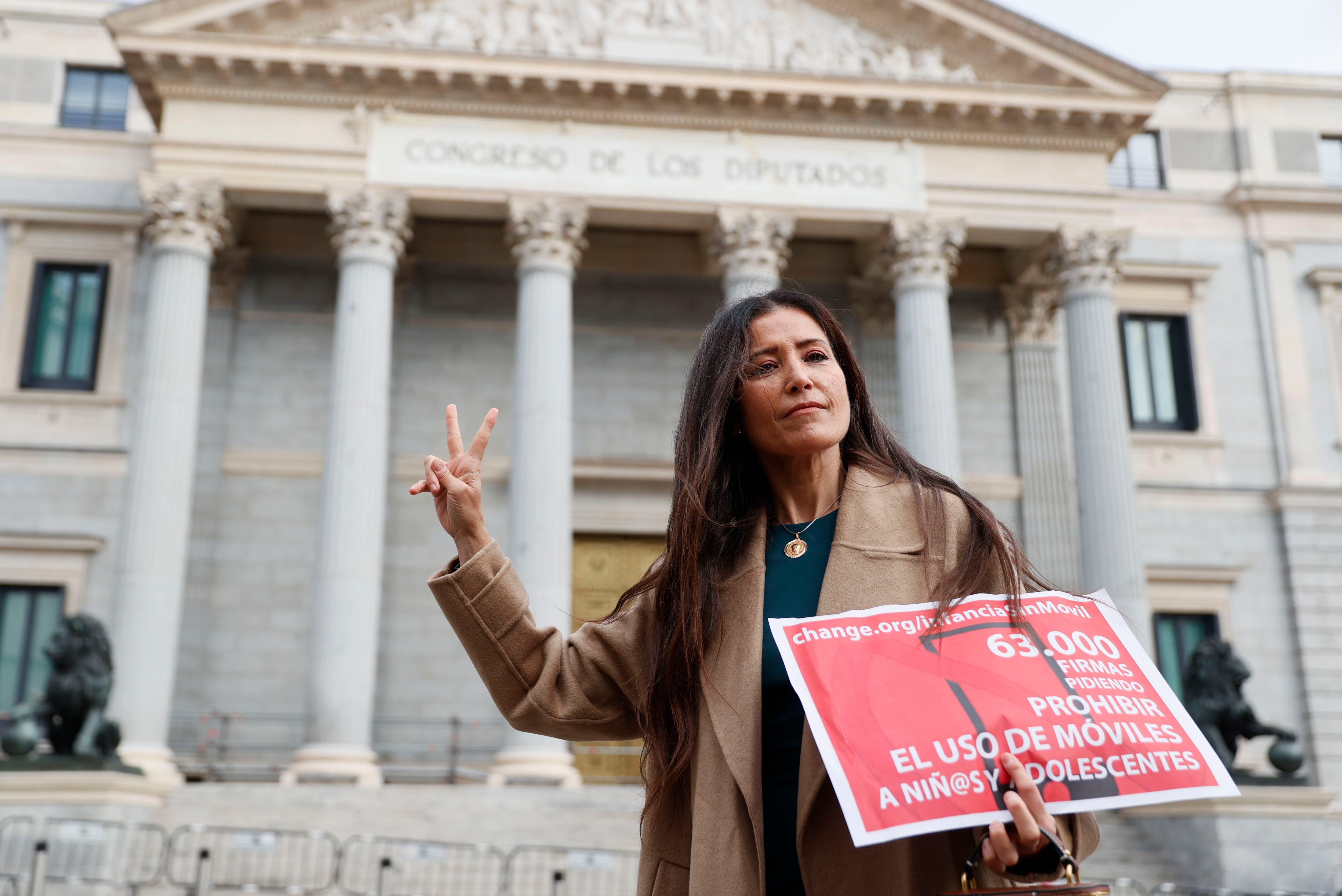 Ángela Sánchez Pérez Merino, docente de la comunidad de Madrid, posa frente al Congreso de los Diputados para presentar la lista de firmas recogidas para una campaña de regulación de los teléfonos móviles en menores, que ha organizado junto a otra decente de secundaria.