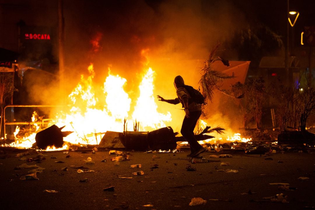 Un manifestante corre frente al fuego durante los disturbios en la Plaza de Urquinaona, en Barcelona el 18 de octubre