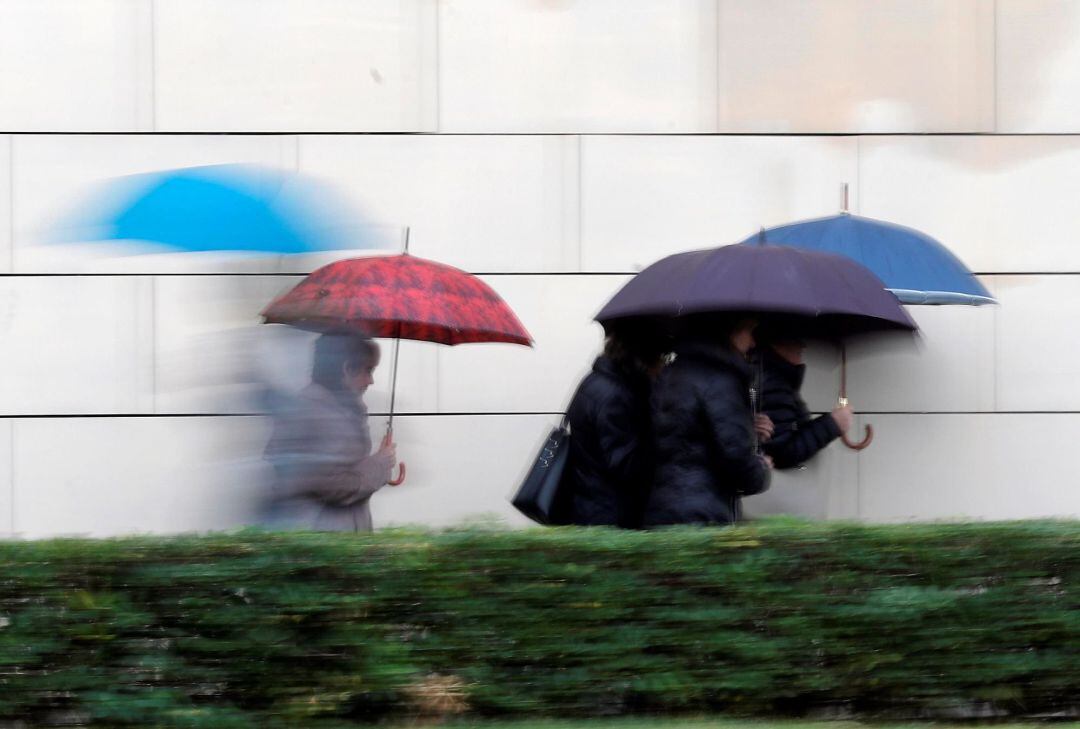 Varias personas se protegen de la lluvia con paraguas 