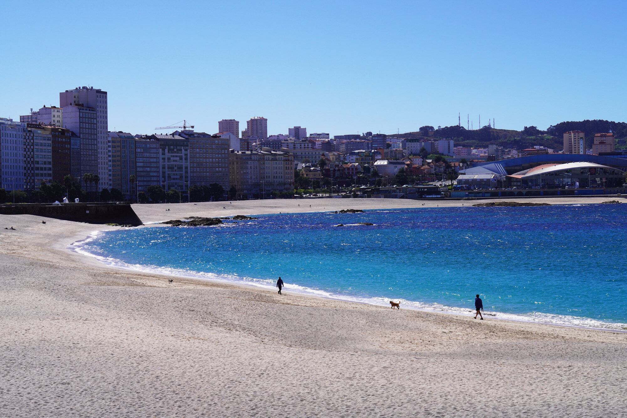 Varias personas caminan por la orilla de las playas Orzán y Riazo