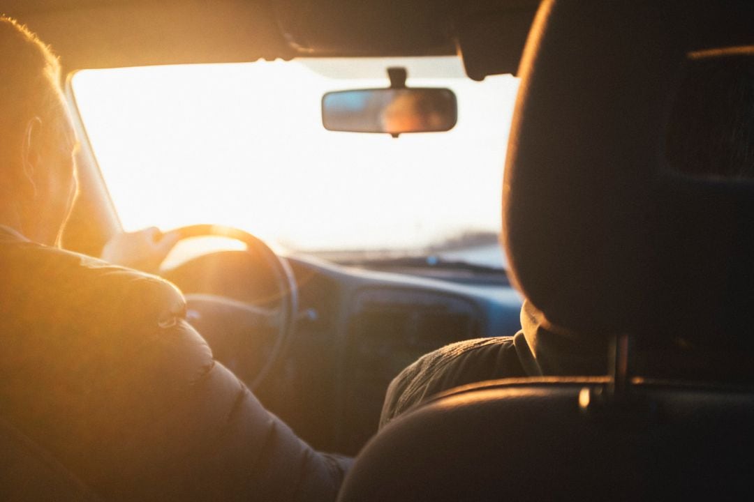 Hombre conduciendo visto desde el asiento trasero del vehículo.