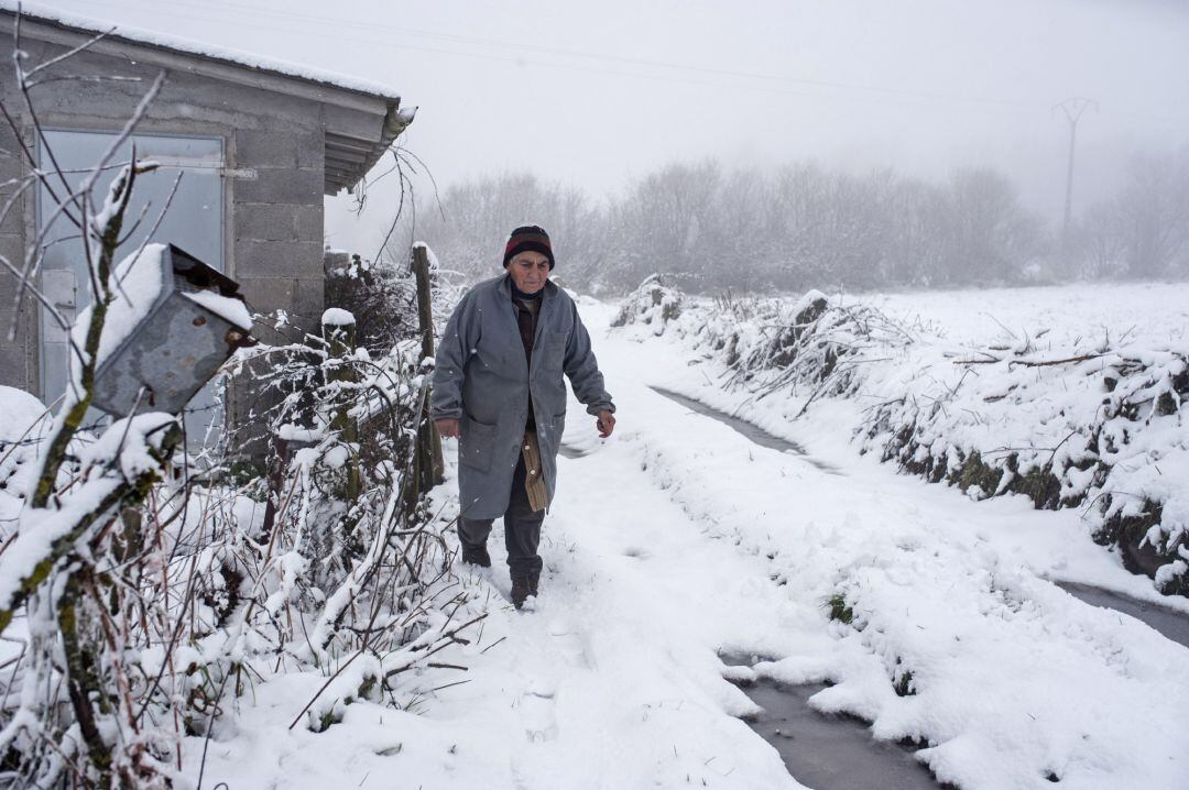 Imagen de archivo de una mujer caminando por la nieve en un pueblo de la montaña de Ourense