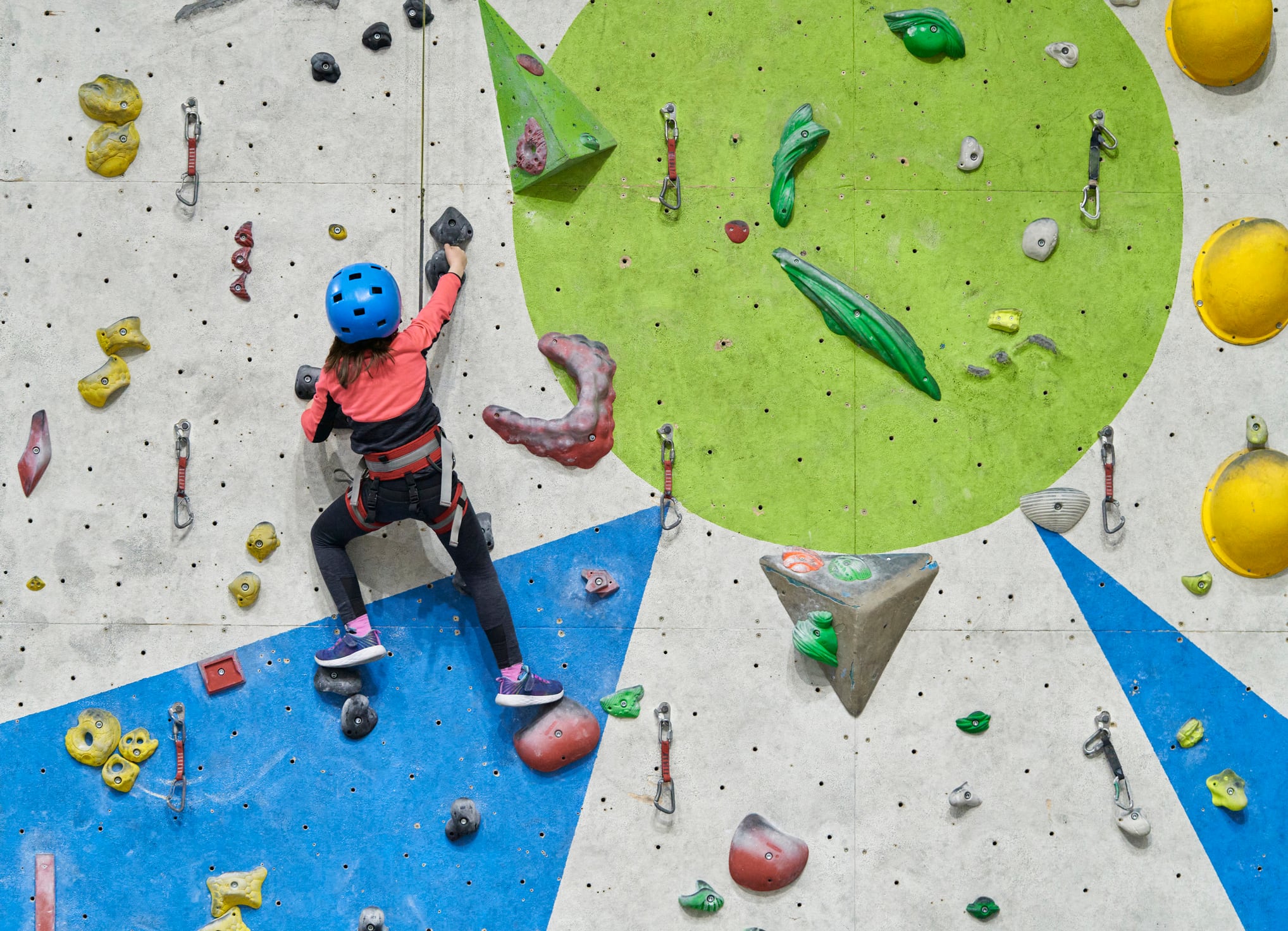 Niña escalando en un rocódromo