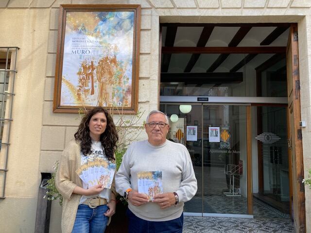 Salomé Beneyto y Paco Vicedo junto al cartel de fiestas de Muro