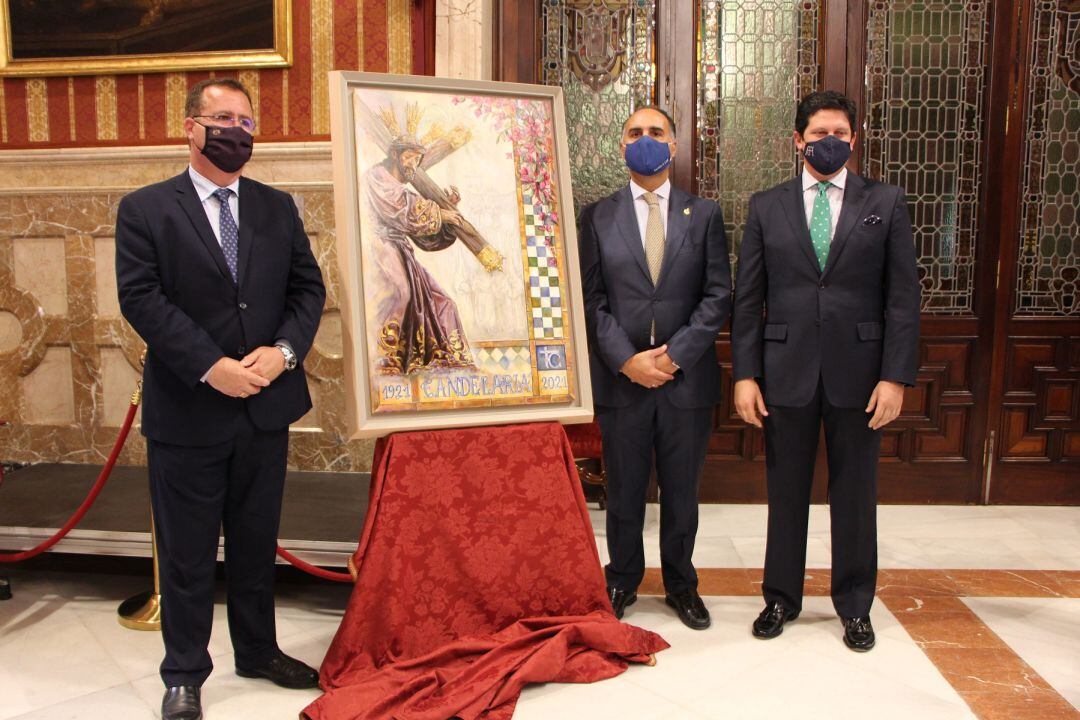 De izquierda a derecha junto al cartel del centenario de La Candelaria, el delegado municipal de Fiestas Mayores, Juan Carlos Cabrera; el hermano mayor Álvaro Delgado y el artista Fernando Aguado