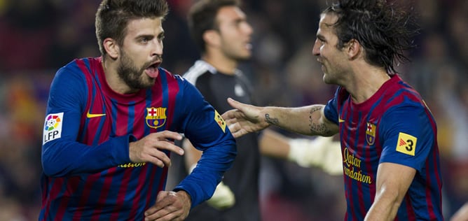 El defensa del F. C. Barcelona, Gerard Piqué (i), celebra con su compañero, Cesc Fábregas, el primer gol del equipo blaugrana, durante el encuentro correspondiente a la decimotercera jornada de liga de primera división, que les enfrenta esta noche al Real