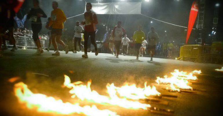 Varios atletas corren iluminados por las antorchas en una carrera de San Antón.