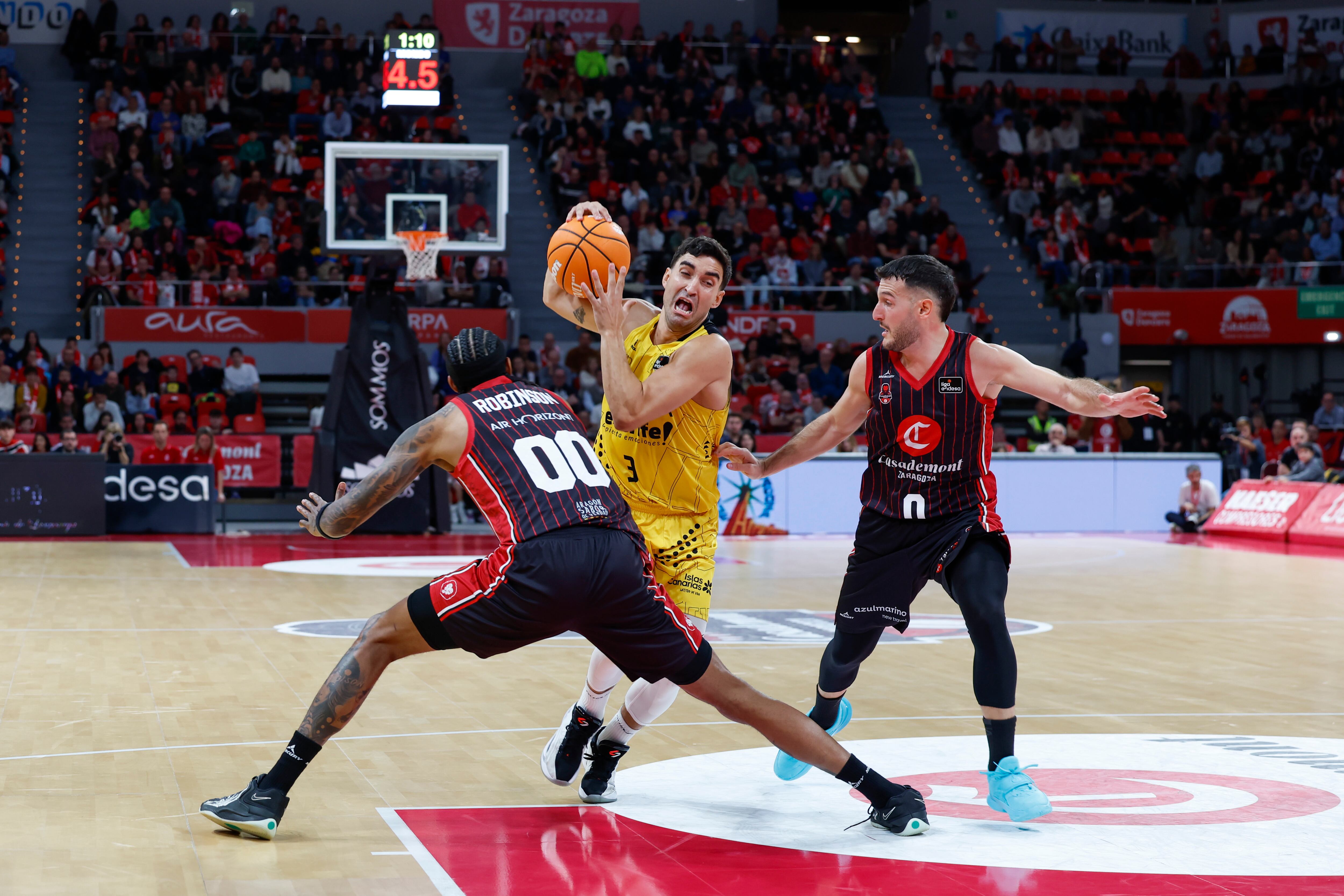 ZARAGOZA, 23/11/2025.- El alero estadounidense del Casademont Zaragoza David Robinson (i) defiende al escolta del La Laguna Tenerife Jaime Fernández (c) durante el partido de Liga Endesa de baloncesto entre el Casademont Zaragoza y el La Laguna Tenerife, este domingo en Zaragoza. EFE/ Javier Cebollada