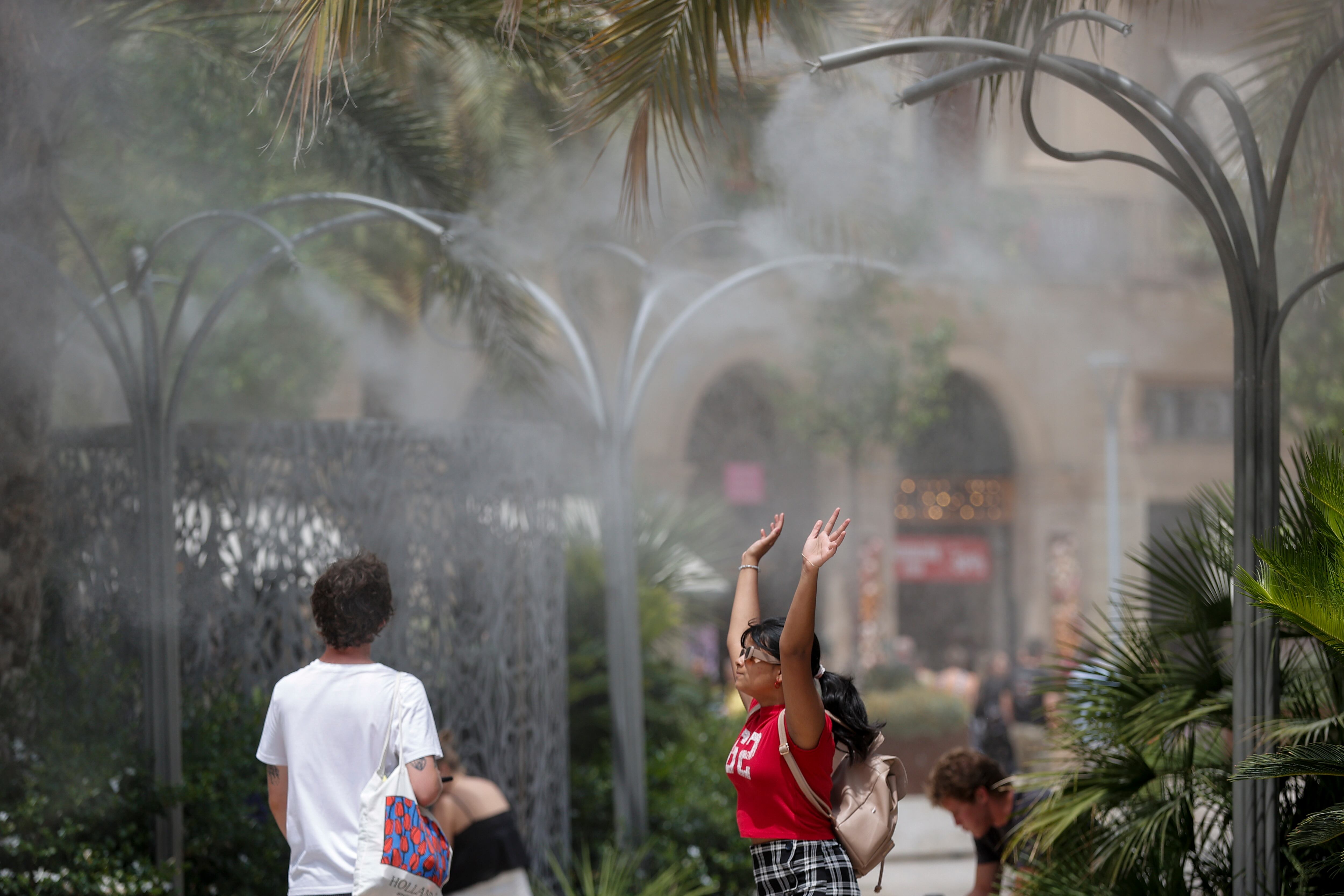 Una persona se refresca bajo un aspersor de agua en  València