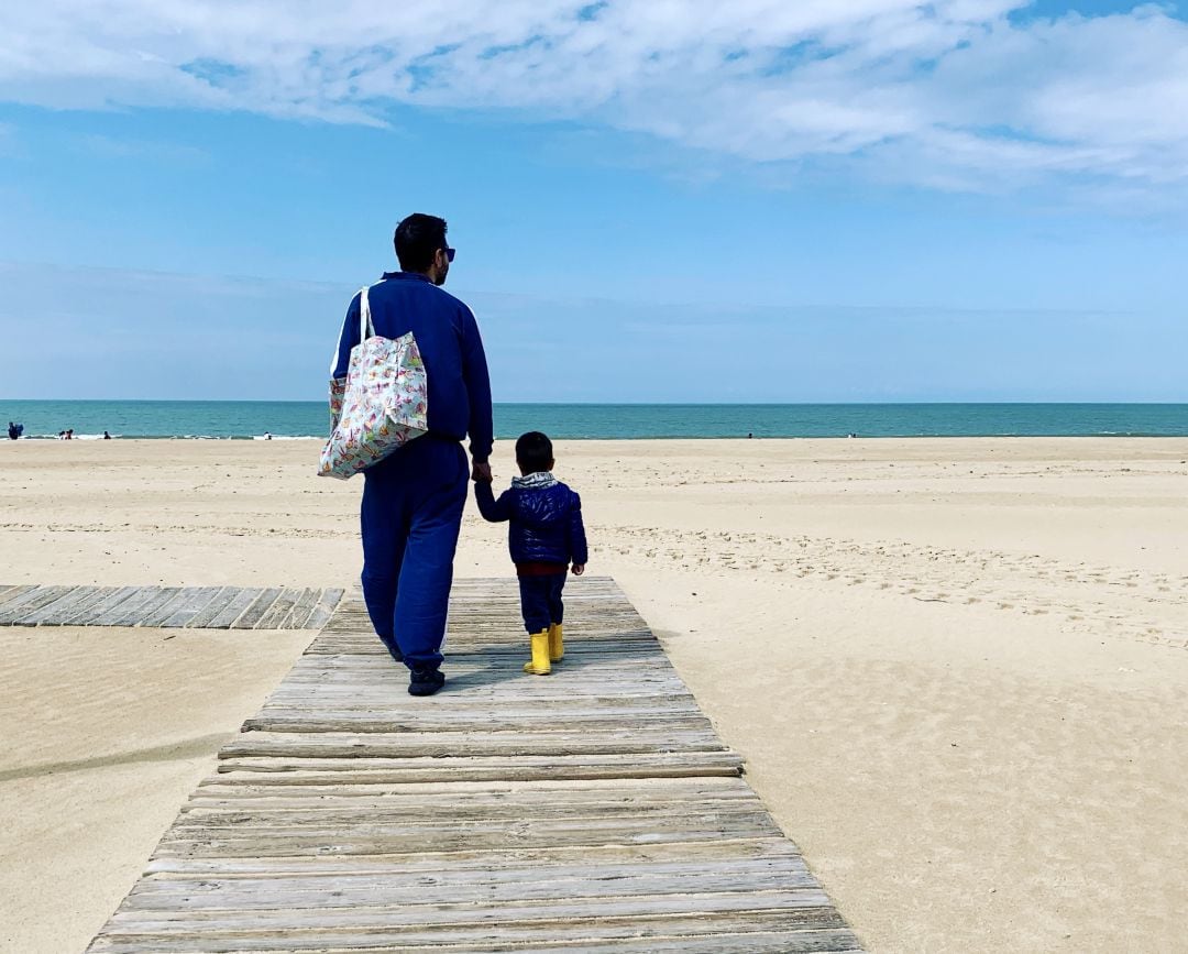 Un padre acompaña a su hijo en el primer paseo por la playa tras el confinamiento