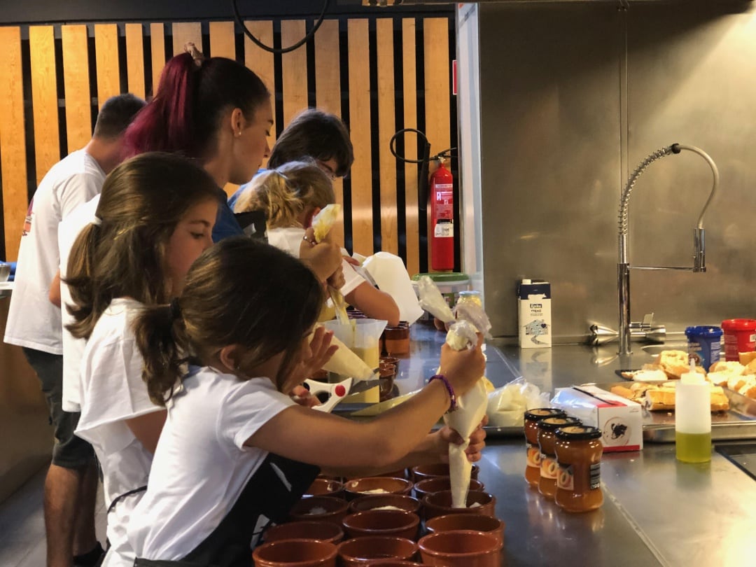 Niñas y niños preparando un goxua en las colonias gastronómicas de la Fundación Abastos