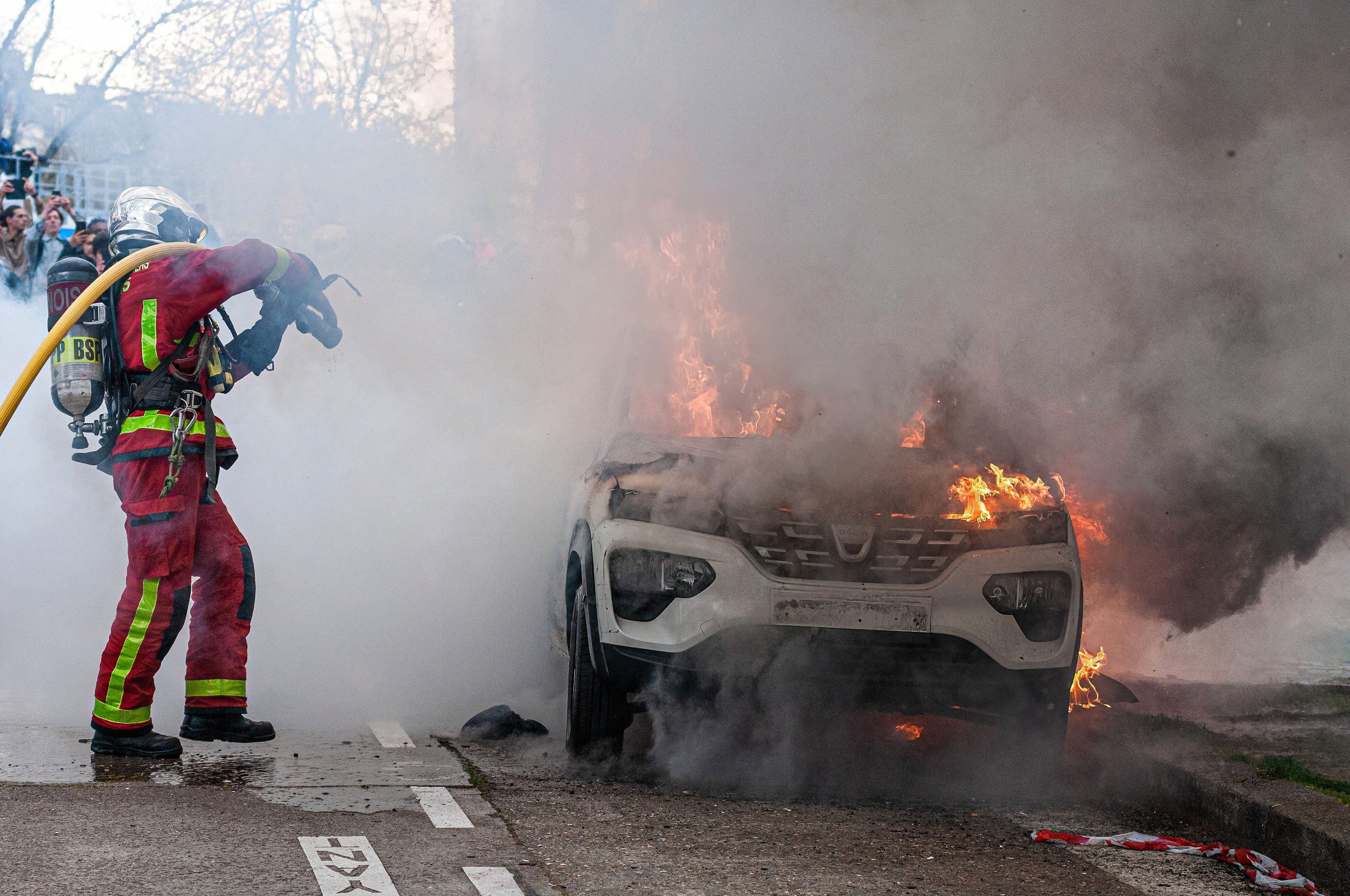 Un bombero trata de sofocar el incendio de un coche en las calles de París (Francia)