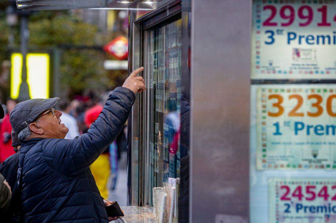 Un hombre señala el décimo de Lotería que quiere comprar en una Administración.