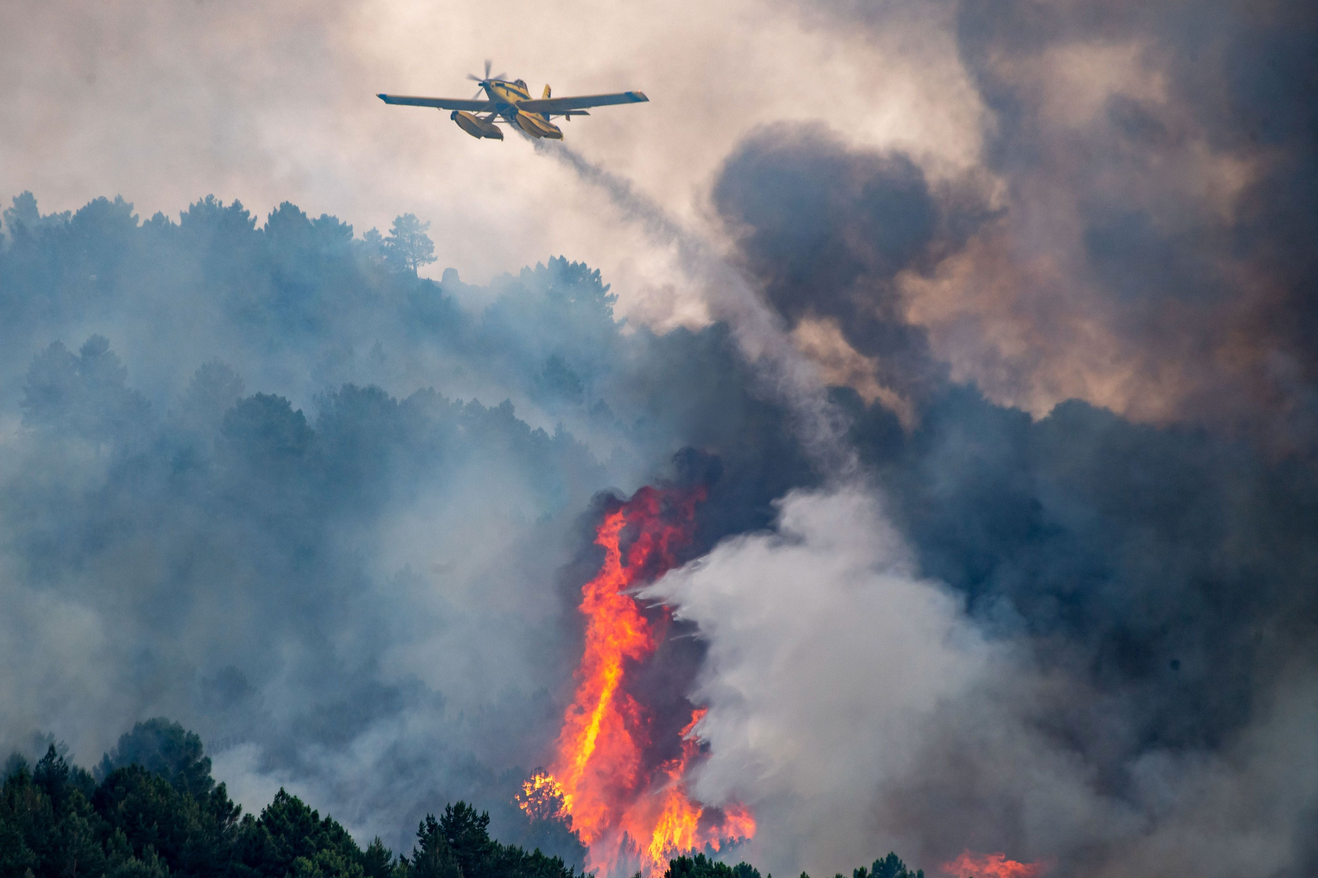 Un avión trabaja en las labores de extinción de un incendio forestal en el cerro del castillo en Collado Mediano (Madrid).