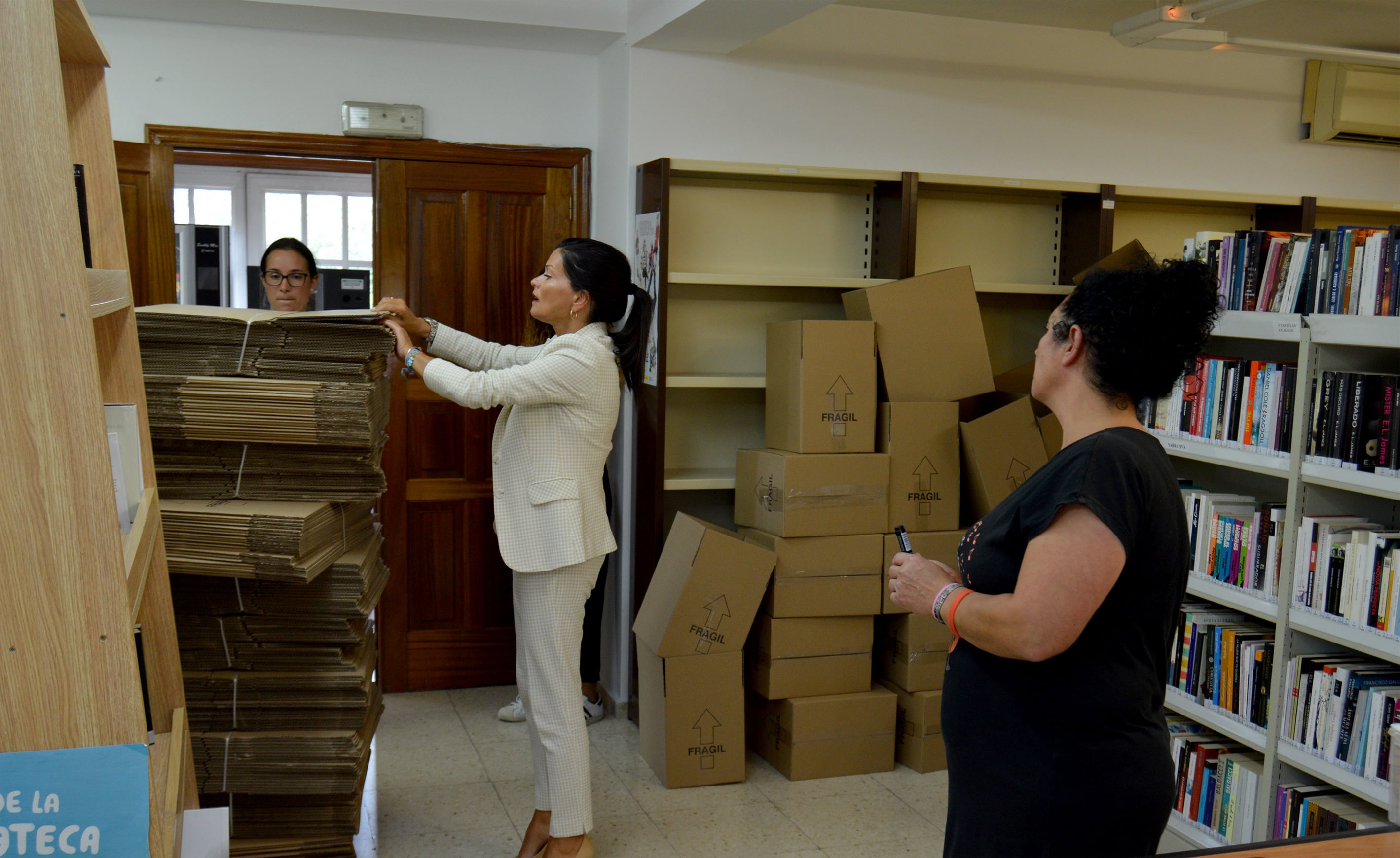 a alcaldesa de Mos, Nidia Arévalo, a arquitecta, Fani Grandal, e a bibliotecaria mosense, Diana Lago, esta mañá na Biblioteca durante os labores de recollida e empaquetado de volumes para o seu traslado.