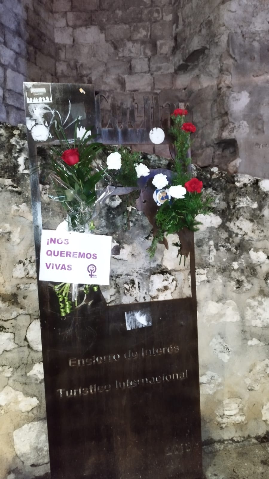 Ramo de flores y cartel en un pequeño monumento de Cuéllar