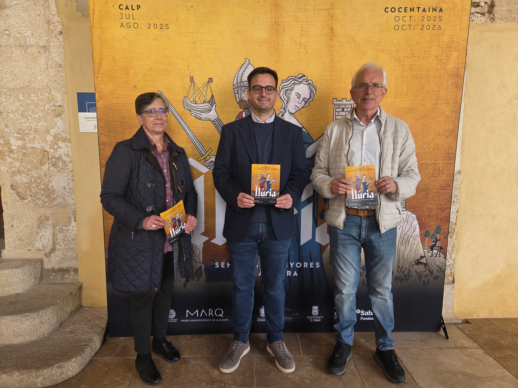 La tècnic Elisa Doménech, l&#039;alcalde Rubén Muñoz i el regidor de Patrimoni Cultural, Paco Payá, davant del cartell anunciador de l&#039;exposició de Roger de Llúria