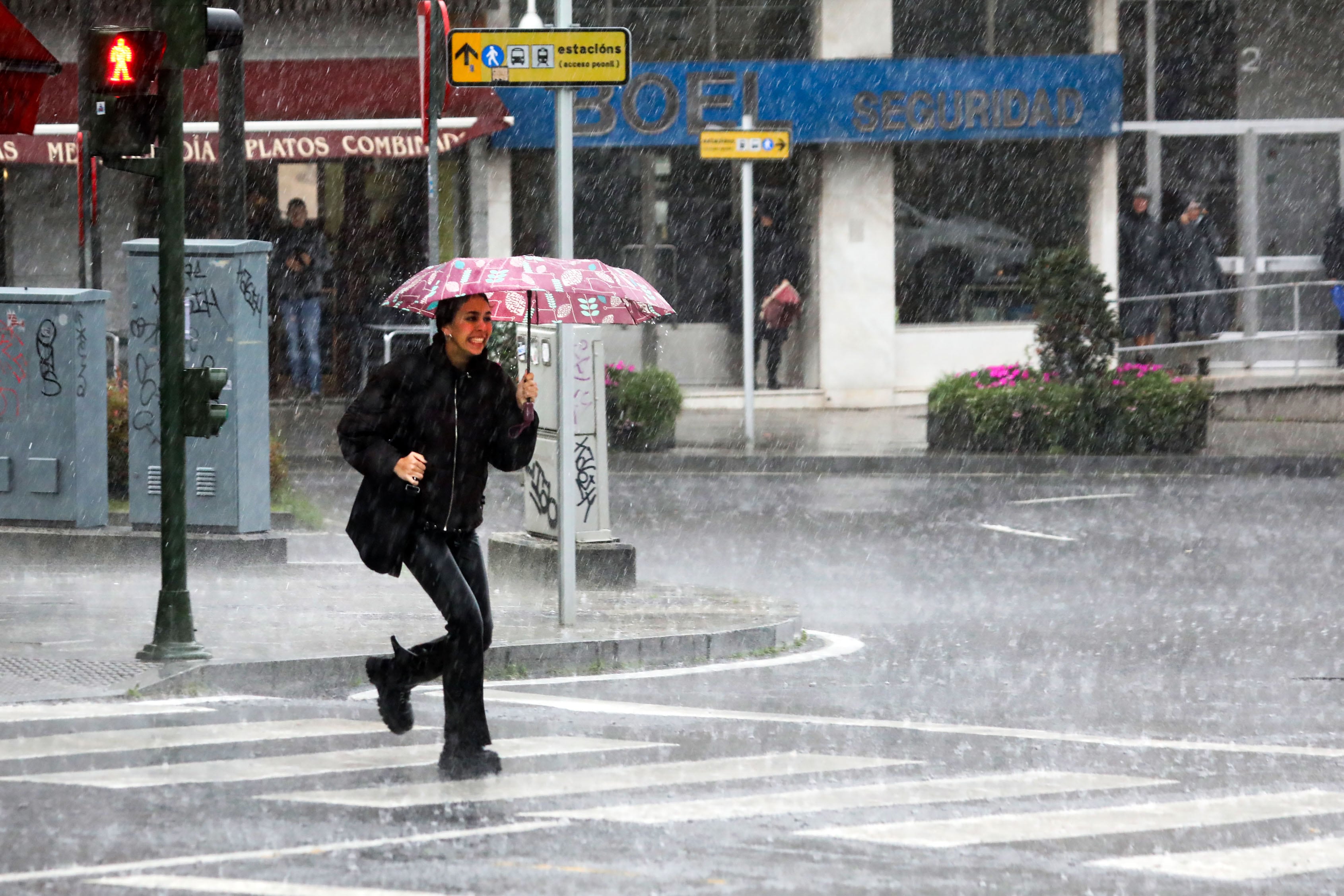 Una mujer pasea bajo la lluvia en Compostela.