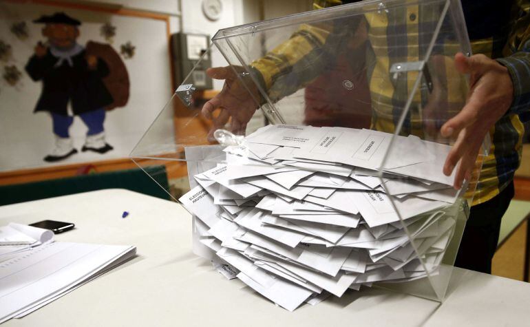 El presidente de una mesa electoral deposita los votos de la urna sobre una mesa para proceder a su recuento. 