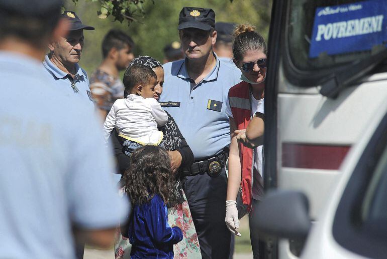 Policías croatas dirigen a varios refugiados a un autobús que les trasladará a un centro de acogida, tras cruzar la frontera con Serbia, en Tovarnik, Croacia