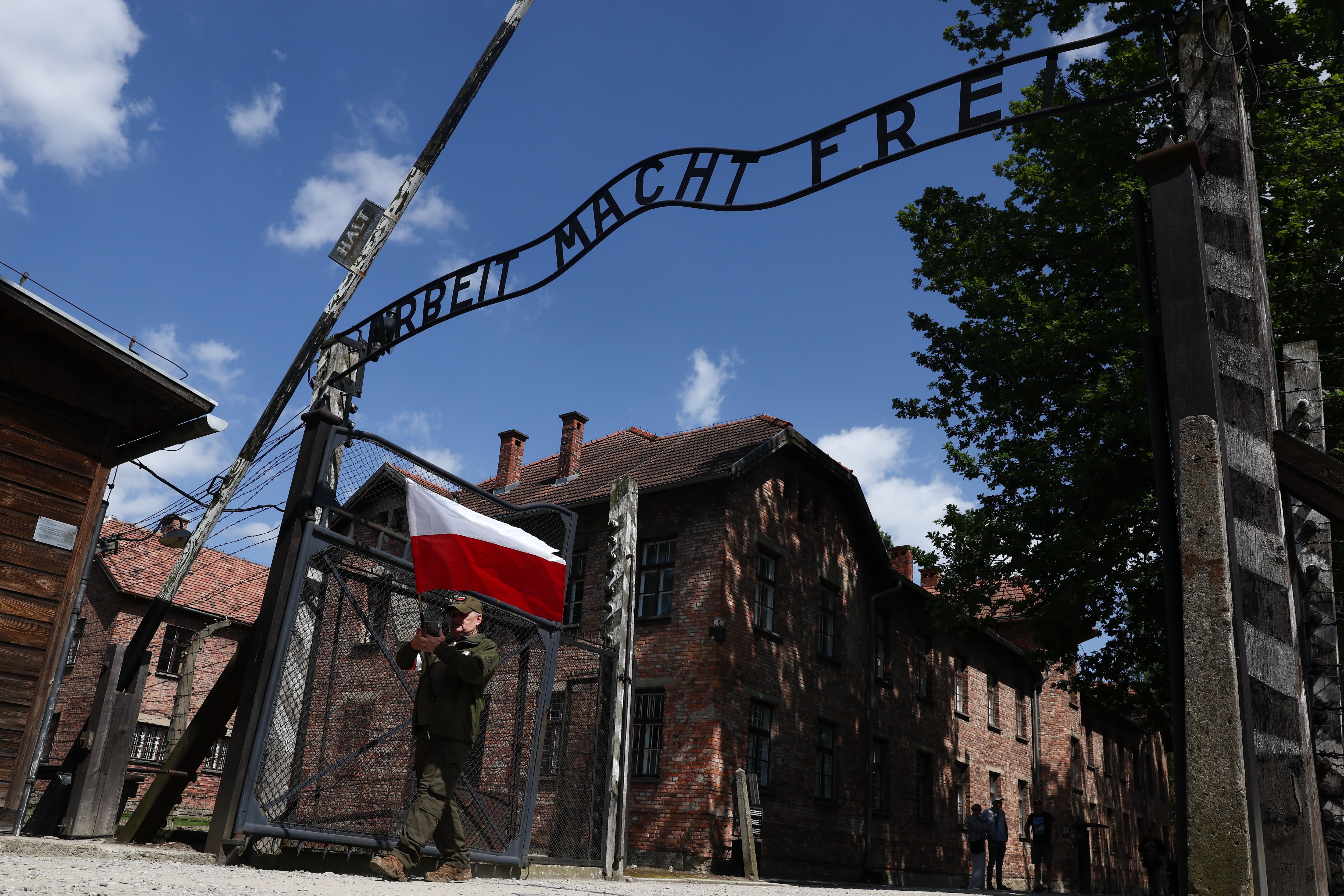 Un hombre con la bandera polaca bajo el arco de entrada al campo de concentración de Auschwitz el pasado mes de junio