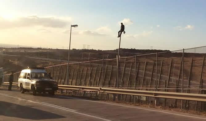 Un inmigrante ha permanecido sentado en una farola hasta que la Guardia Civil ha conseguido bajarle con una grúa