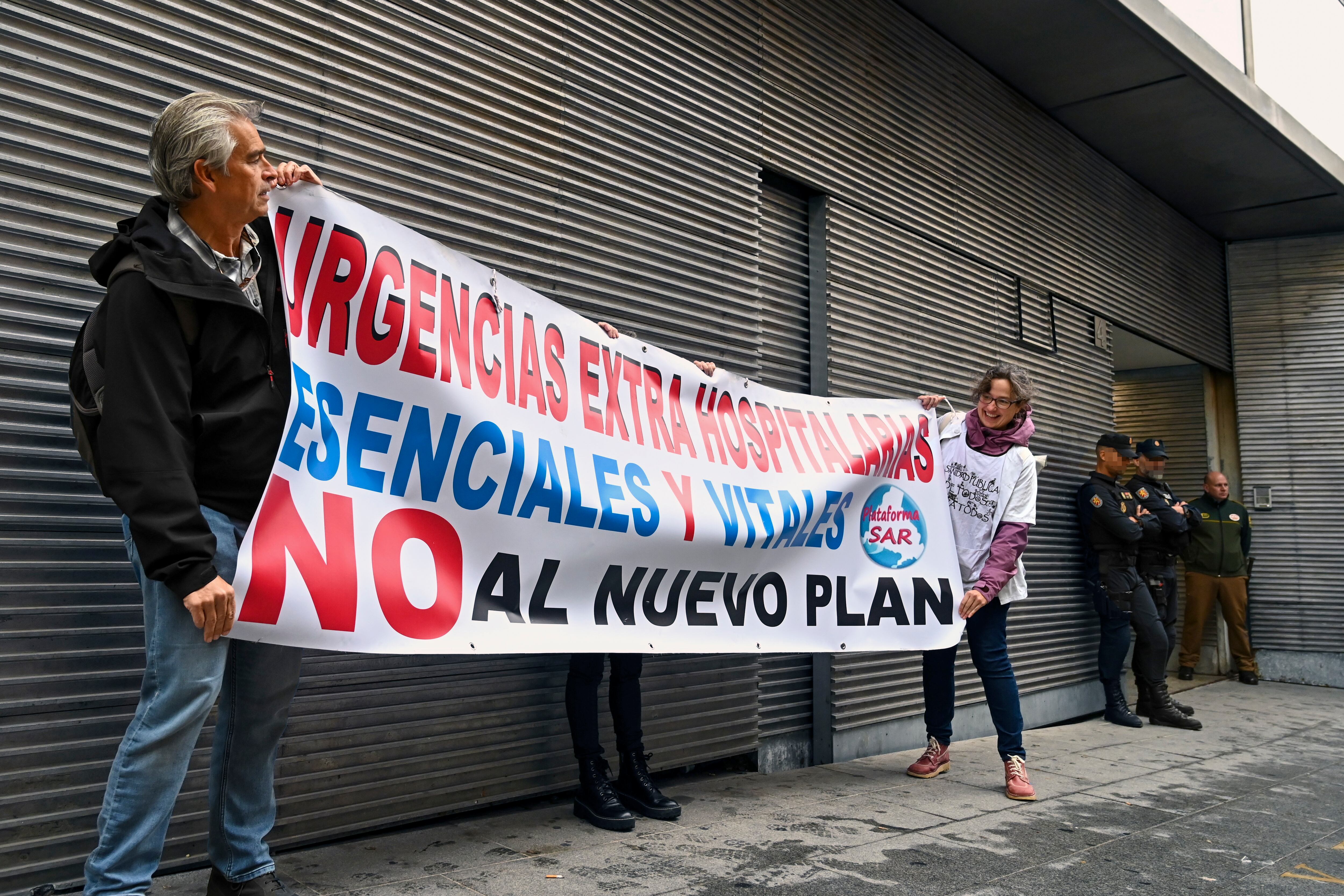 Dos activistas despliegan una pancarta ante el Registro de la Conserjería de Presidencia de la Comunidad de Madrid en el marco de la entrega, este jueves, de las firmas recogidas en defensa de las urgencias extrahospitalarias