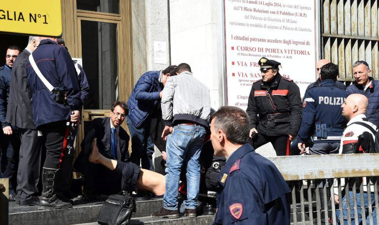 Policías y miembros de los servicios de rescate asisten a un herido a las puertas del Palacio de Justicia en Milán.