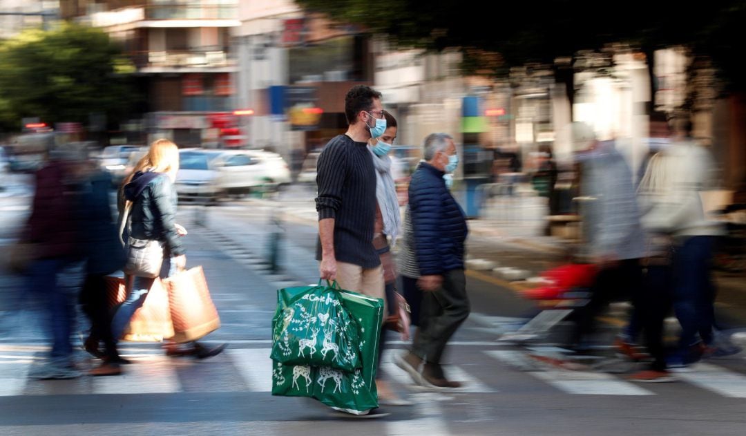 Varias personas cargan con sus bolsas tras realizar sus compras este domingo a menos de dos semanas de celebrarse la navidad.