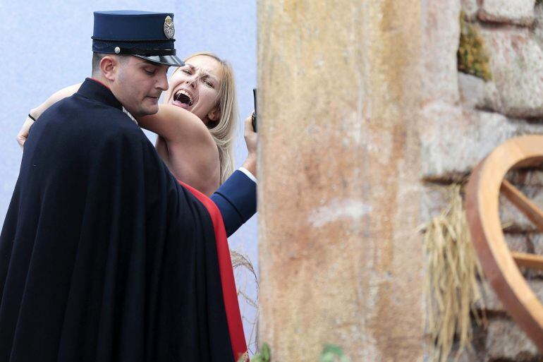 Un miembro de la gendarmería vaticana cubre y detiene a una activista de Femen que intentó llevarse la figura del niño Jesús del belén instalado en la Plaza de San Pedro del Vaticano