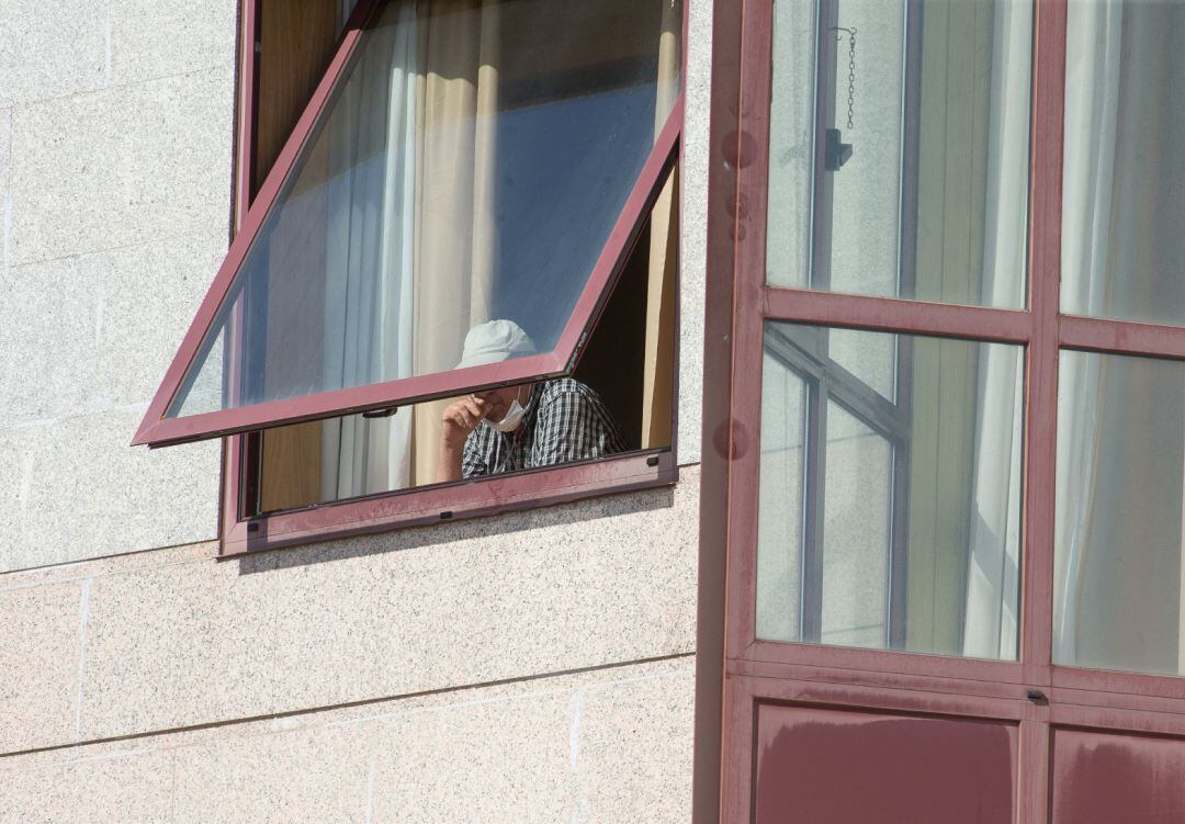 Una persona se asoma por la ventana de una residencia de mayores