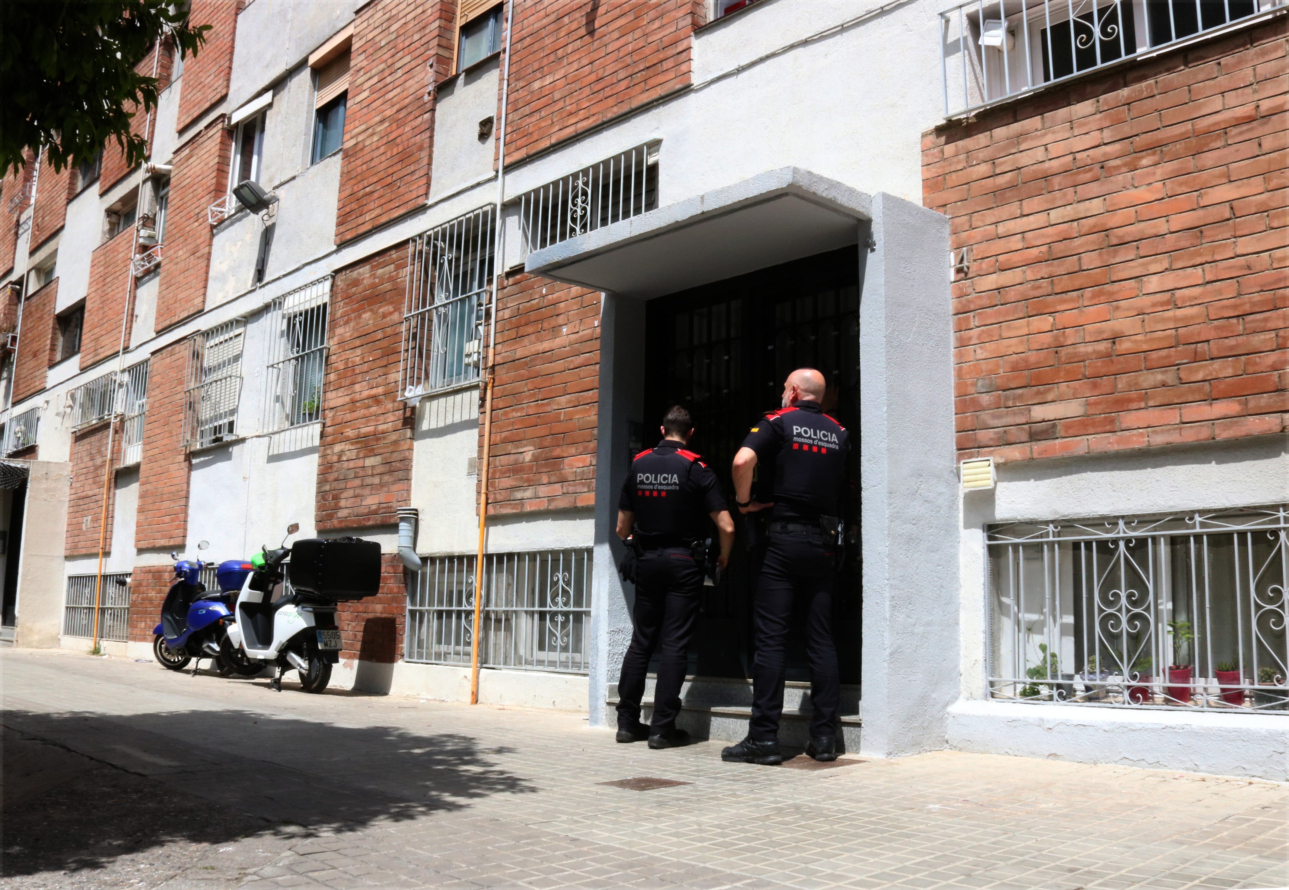 Dos agents dels Mossos a l'entrada de l'edifici de Barcelona on van trobar el cadàver de la víctima