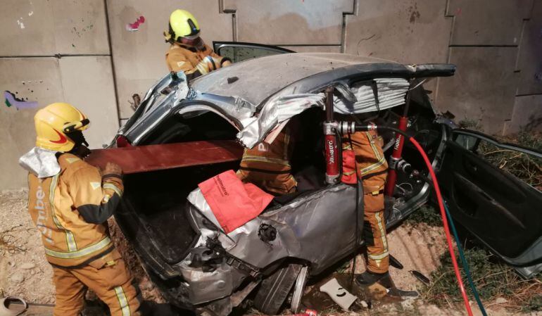 Los bomberos trabajan en el rescate de dos personas atrapadas en su vehículo, en un accidente cerca del peaje de San Juan.