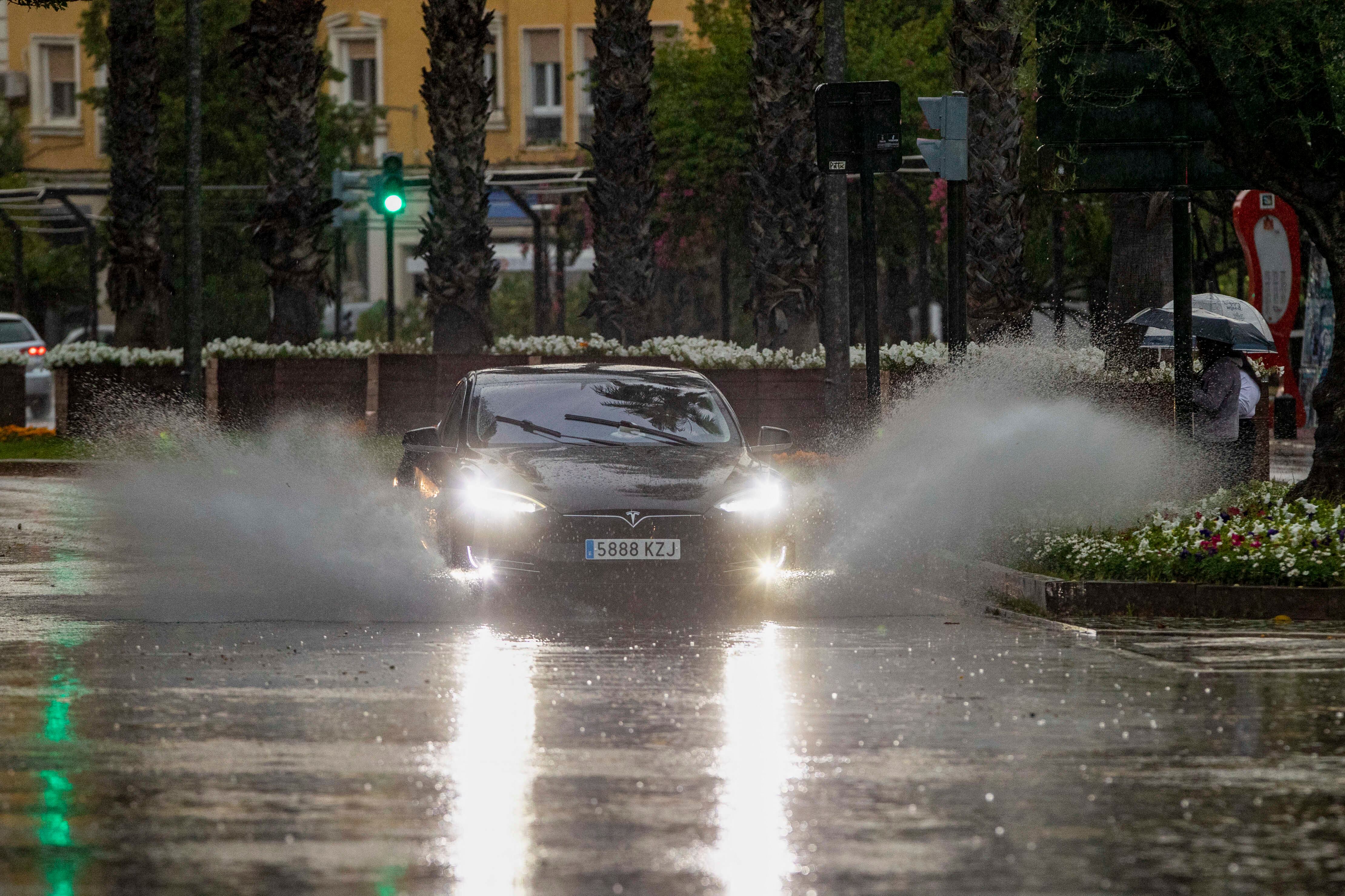 Un coche levanta el agua de la lluvia caída en la tarde de este domingo en la ciudad de Murcia