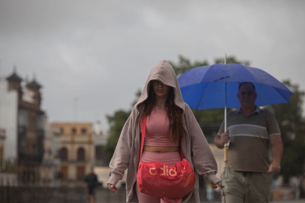 Dos viandantes se protegen de la lluvia en Sevilla.