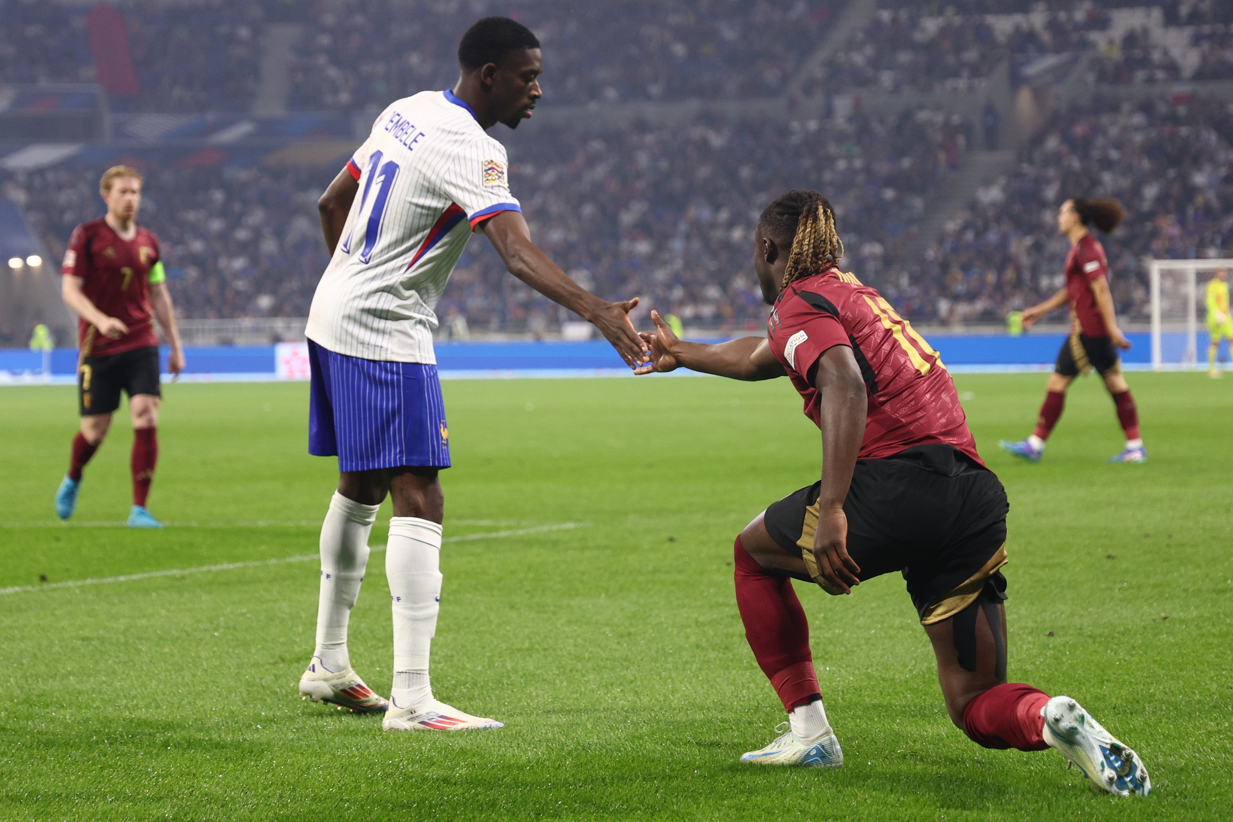 Osmane Dembélé tiende la mano a Jeremy Doku durante el Francia-Bélgica