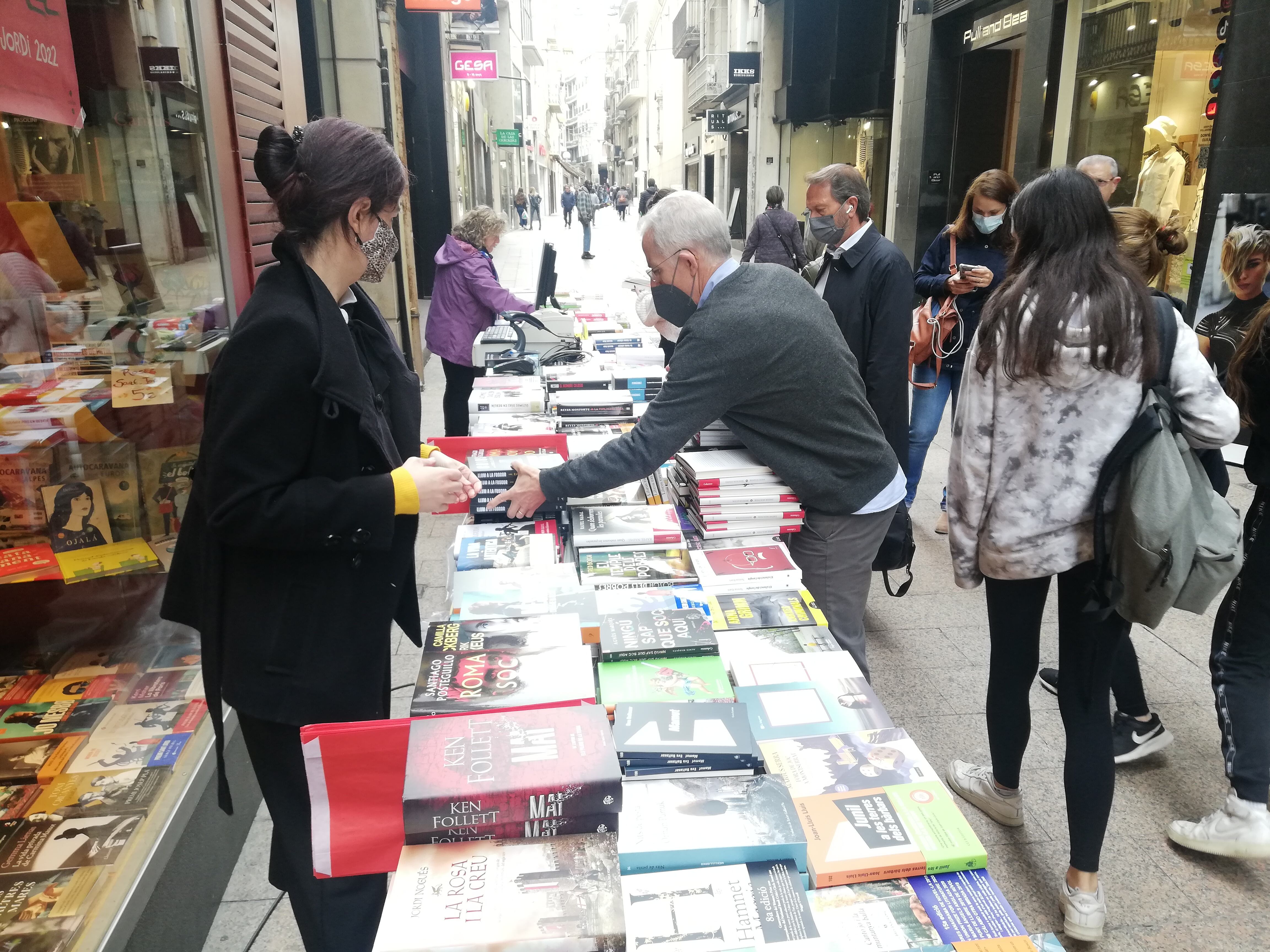 No és Sant Jordi però casi. Jordi Caselles reposa llibres a la parada que han muntat davant la llibreria en aquesta vigília de Sant Jordi.