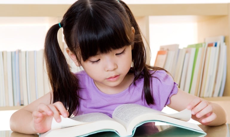 Imagen de una niña japonesa leyendo un libro.