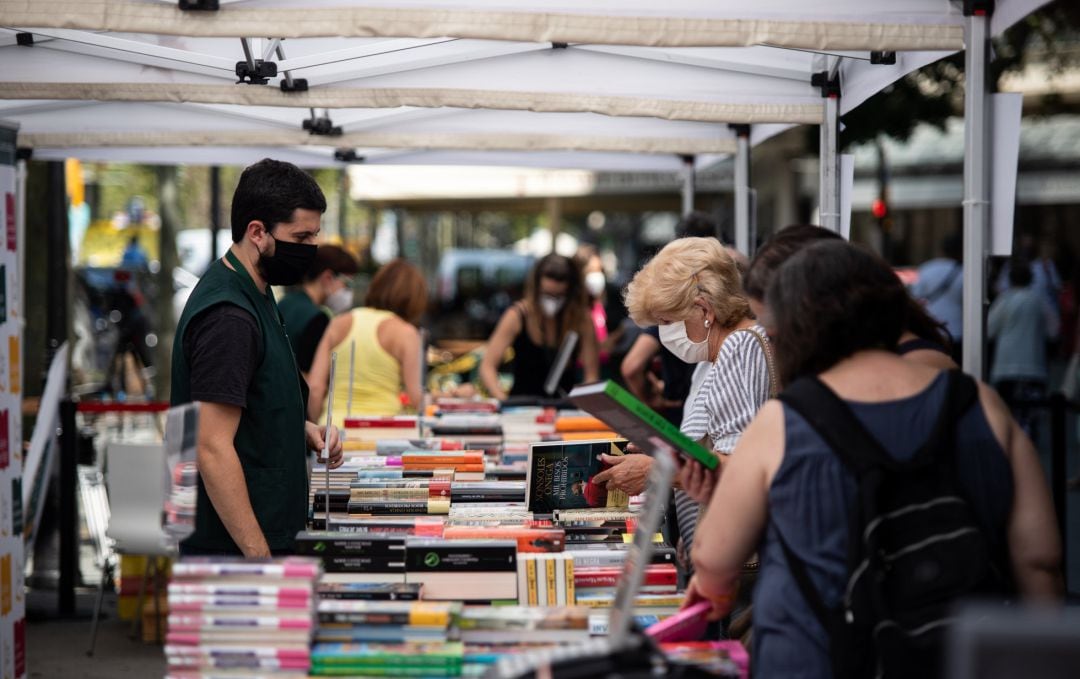 Varios personas observan libros en varios puestos de libros colocados en la calle, en Barcelona.
